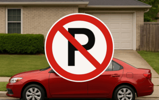 Rød personbil parkeret på gaden foran et parcelhus med et stort parkeringsforbudsskilt (bogstav P med skråstreg) henover bilen.